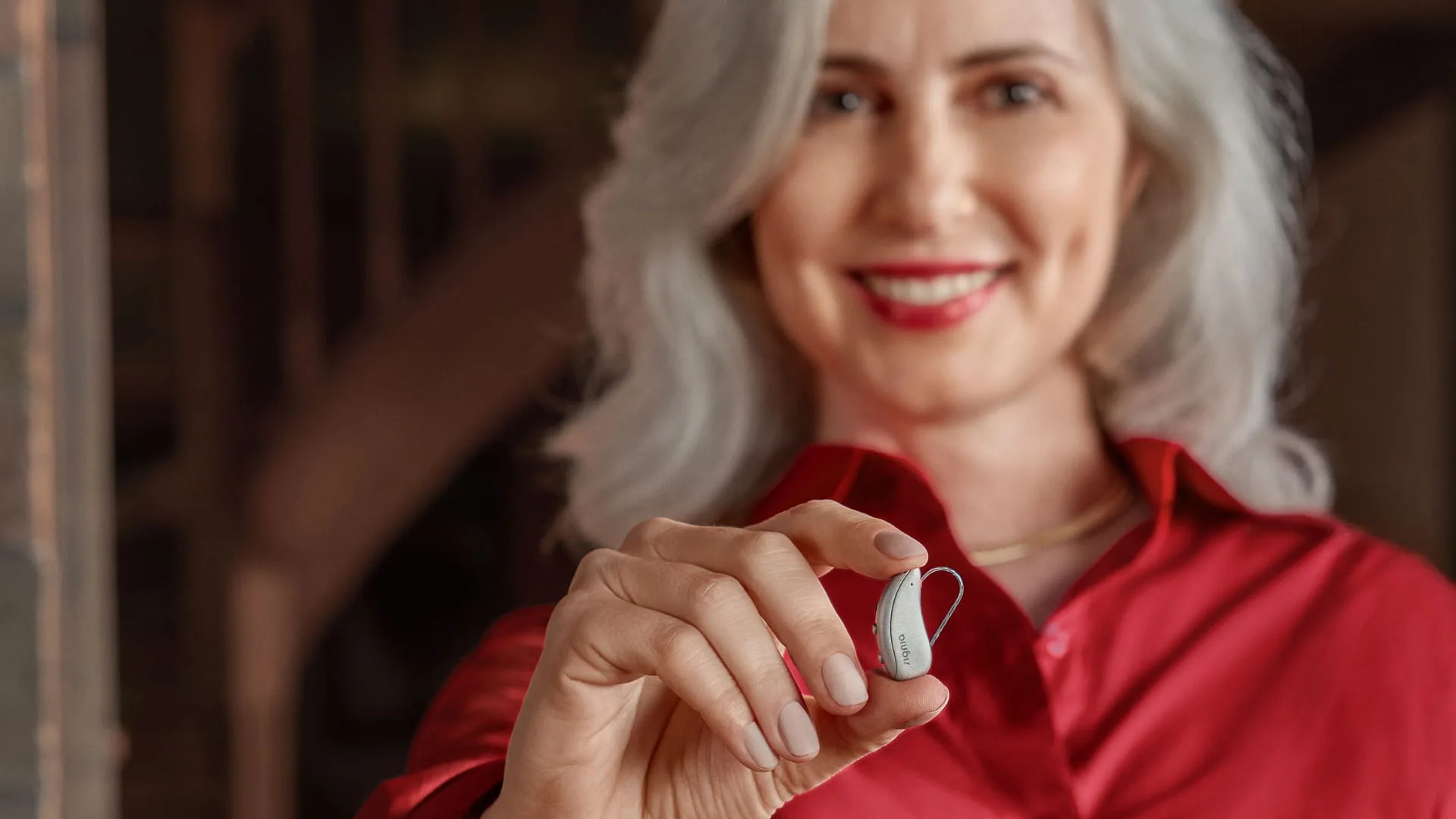 A woman holding a Signia Pure Charge&Go MaX hearing aid